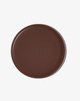 A pan of BRONZOUR cream bronzer with a dark brown to chocolate color, featuring the brand's monogram 'TJ' embossed in the center.
