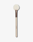 A cream coloured fan shaped makeup brush with white brush hairs with logo 'taniellejai'