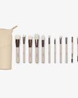 A set of twelve makeup brushes with beige handles and white bristles, displayed alongside a cream vegan leather case.