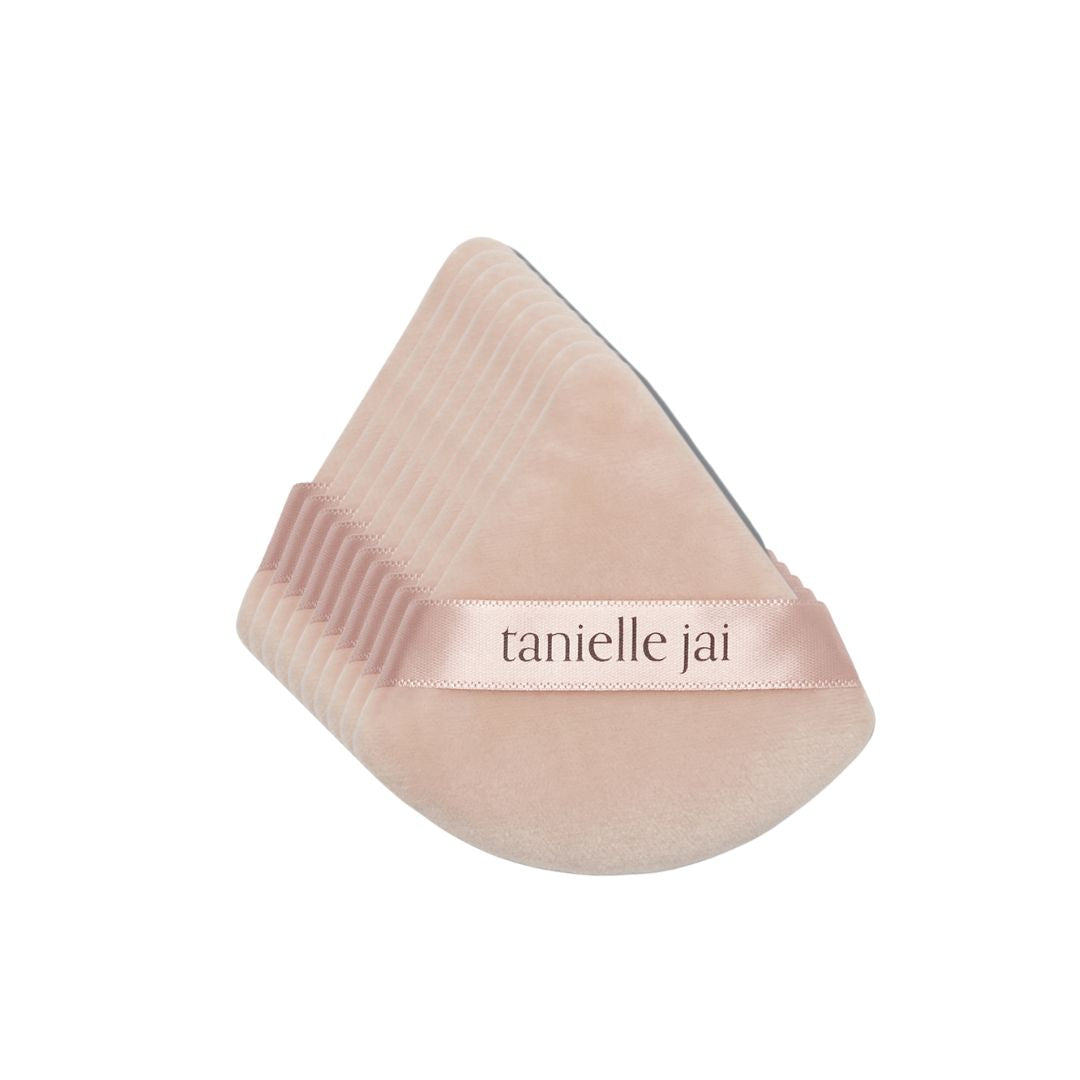 A pack of 10 triangular pink velvet powder puffs with the logo 'tanielle jai' featured across the center.