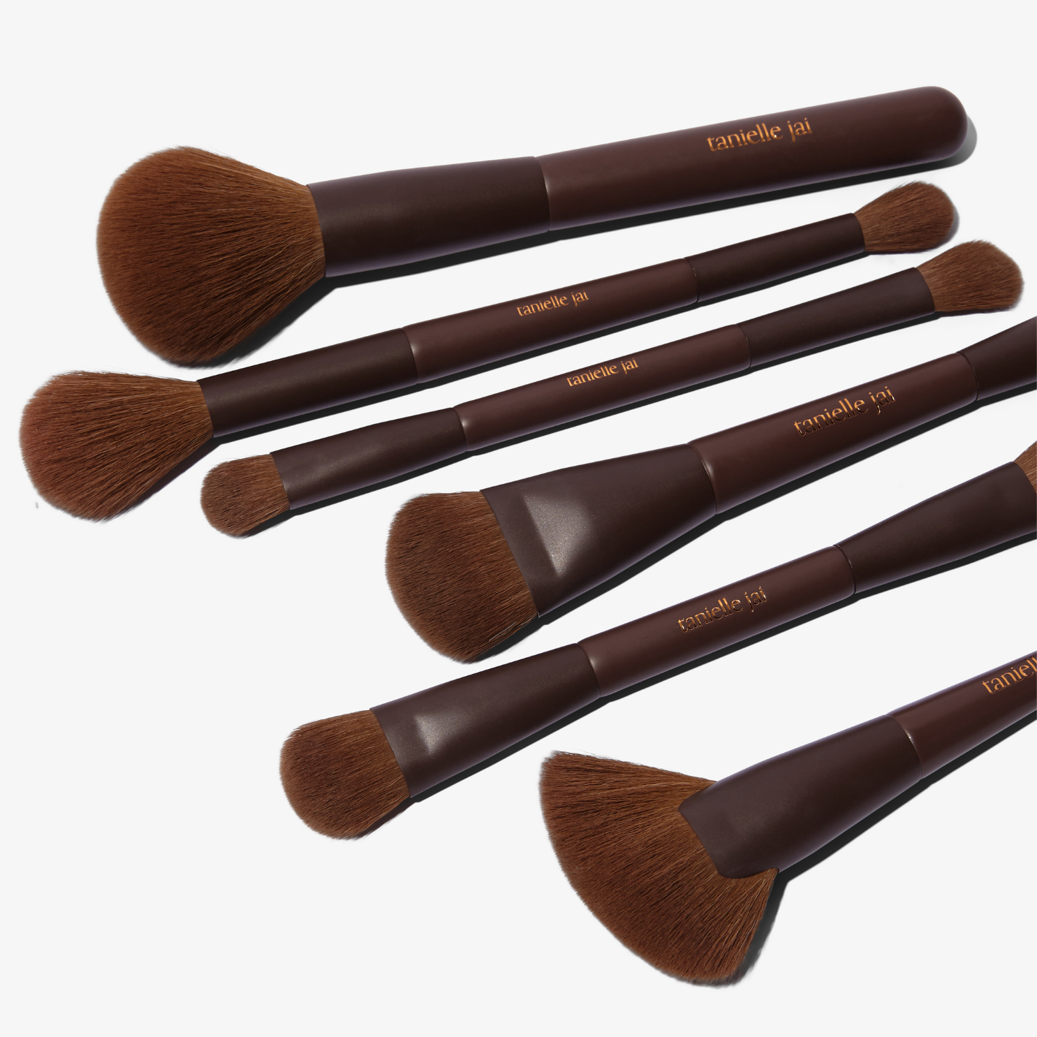 A set of 11, mostly dual-ended makeup brushes with brown handles and hypoallergenic synthetic bristles, displayed alongside a brown vegan magnetic brush clutch.