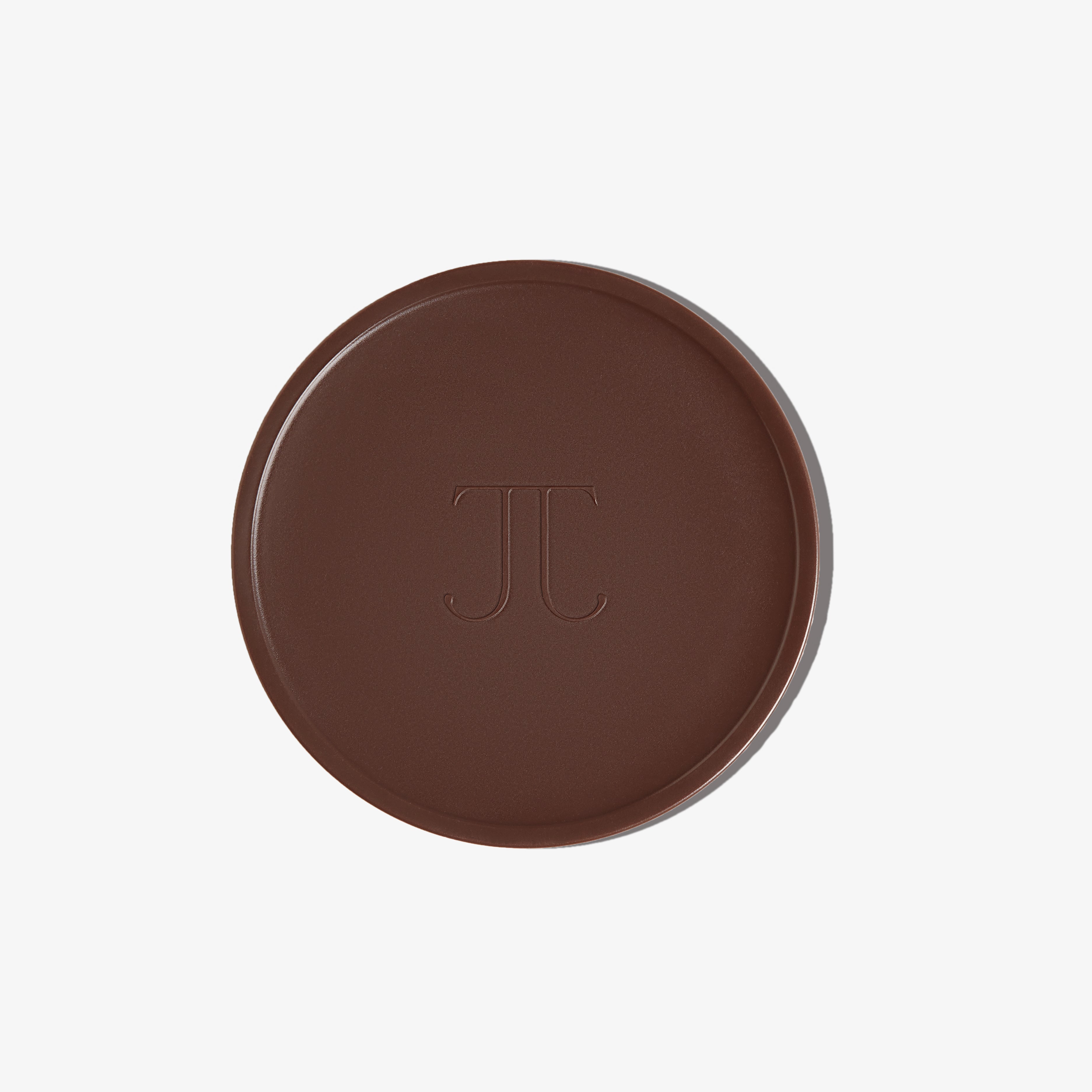 A pan of BRONZOUR cream bronzer with a dark brown to chocolate color, featuring the brand's monogram 'TJ' embossed in the center.