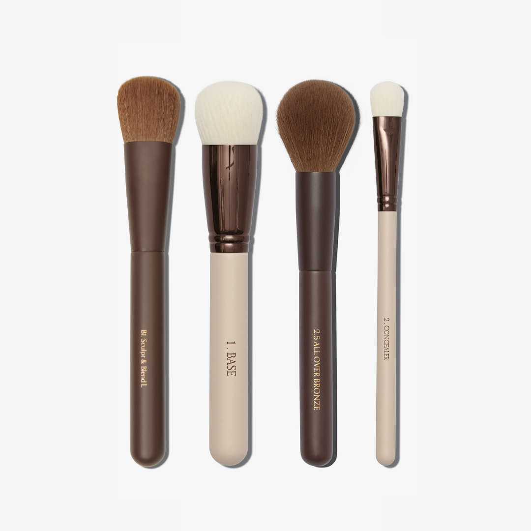 Set of four makeup brushes with brown and beige handles on a white background