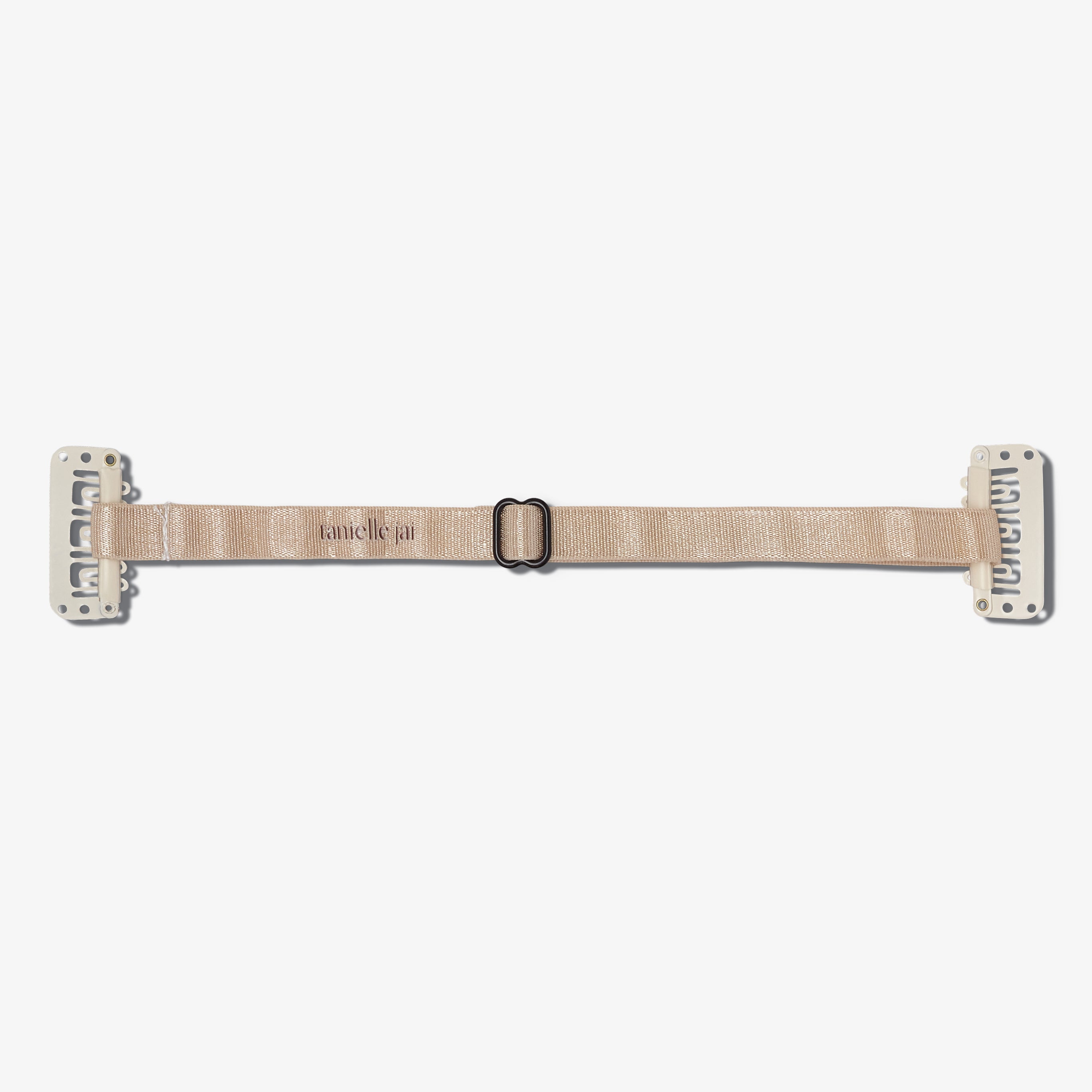 A beige hair clip with clips on the ends, branded 'tanielle jai'.