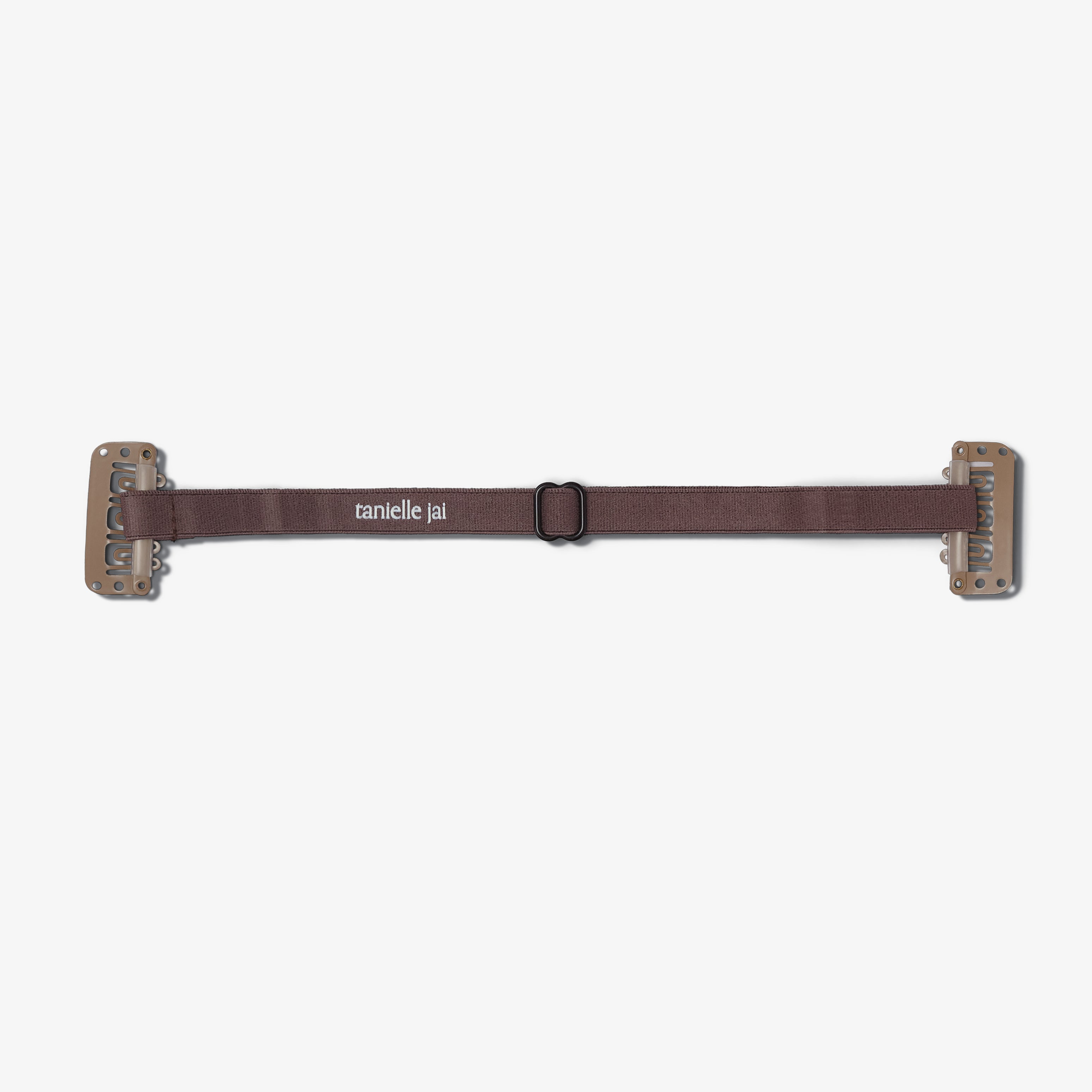 A brown hair clip with clips on the ends, branded 'tanielle jai'.