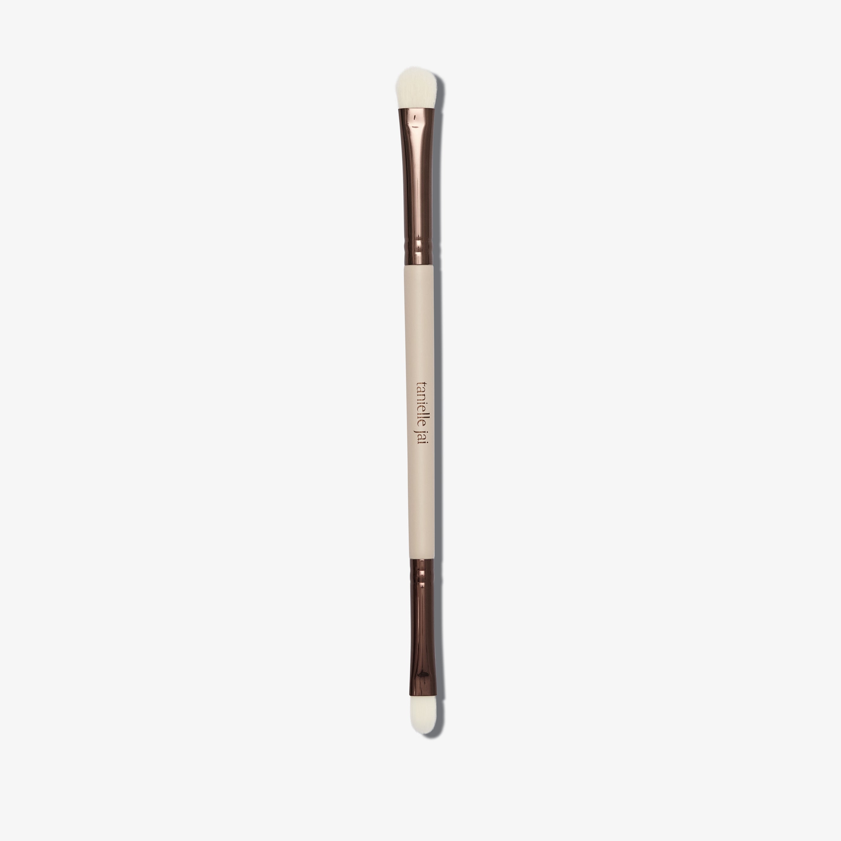 A dual-ended makeup brush with a beige handle and synthetic bristles, one end flat and wide, and the other end rounded for lip definition.