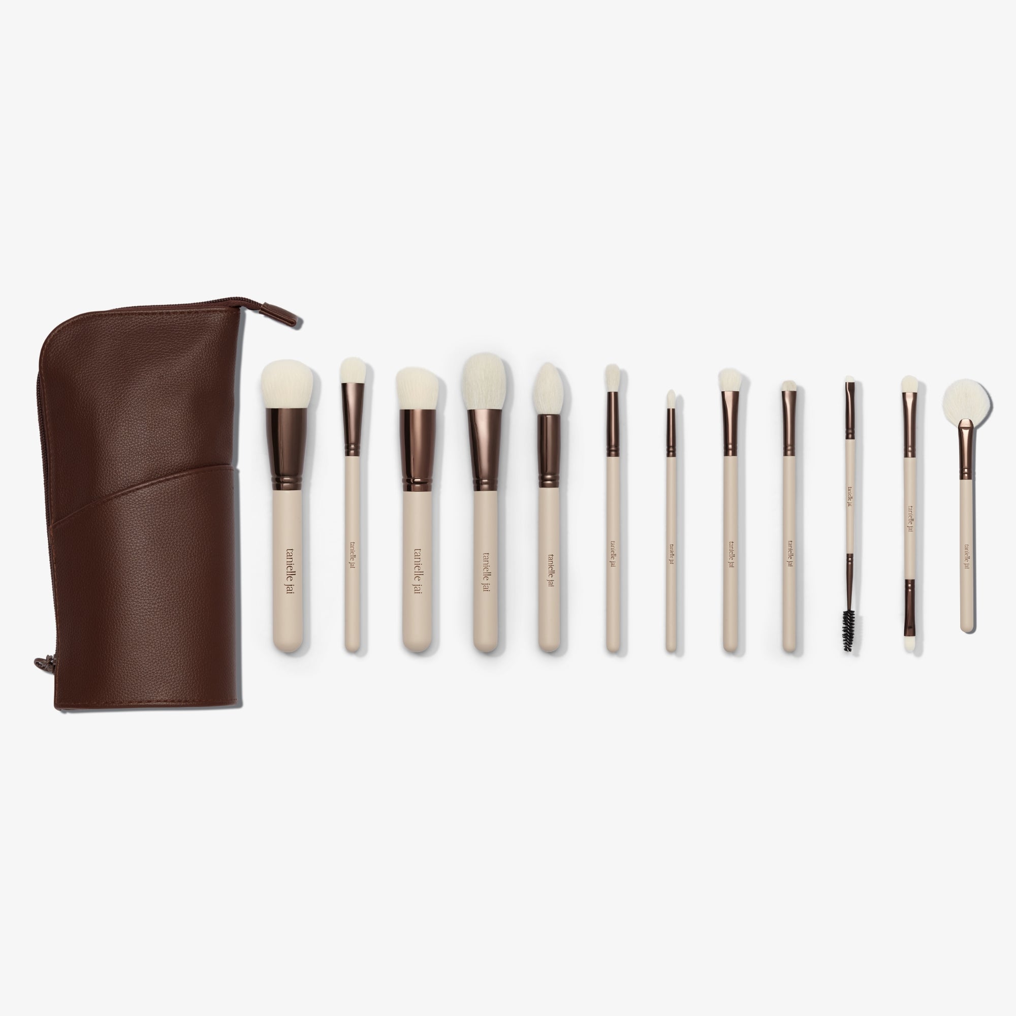 A set of twelve makeup brushes with beige handles and white bristles, displayed alongside a brown vegan leather case. 