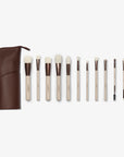 A set of twelve makeup brushes with beige handles and white bristles, displayed alongside a brown vegan leather case. 