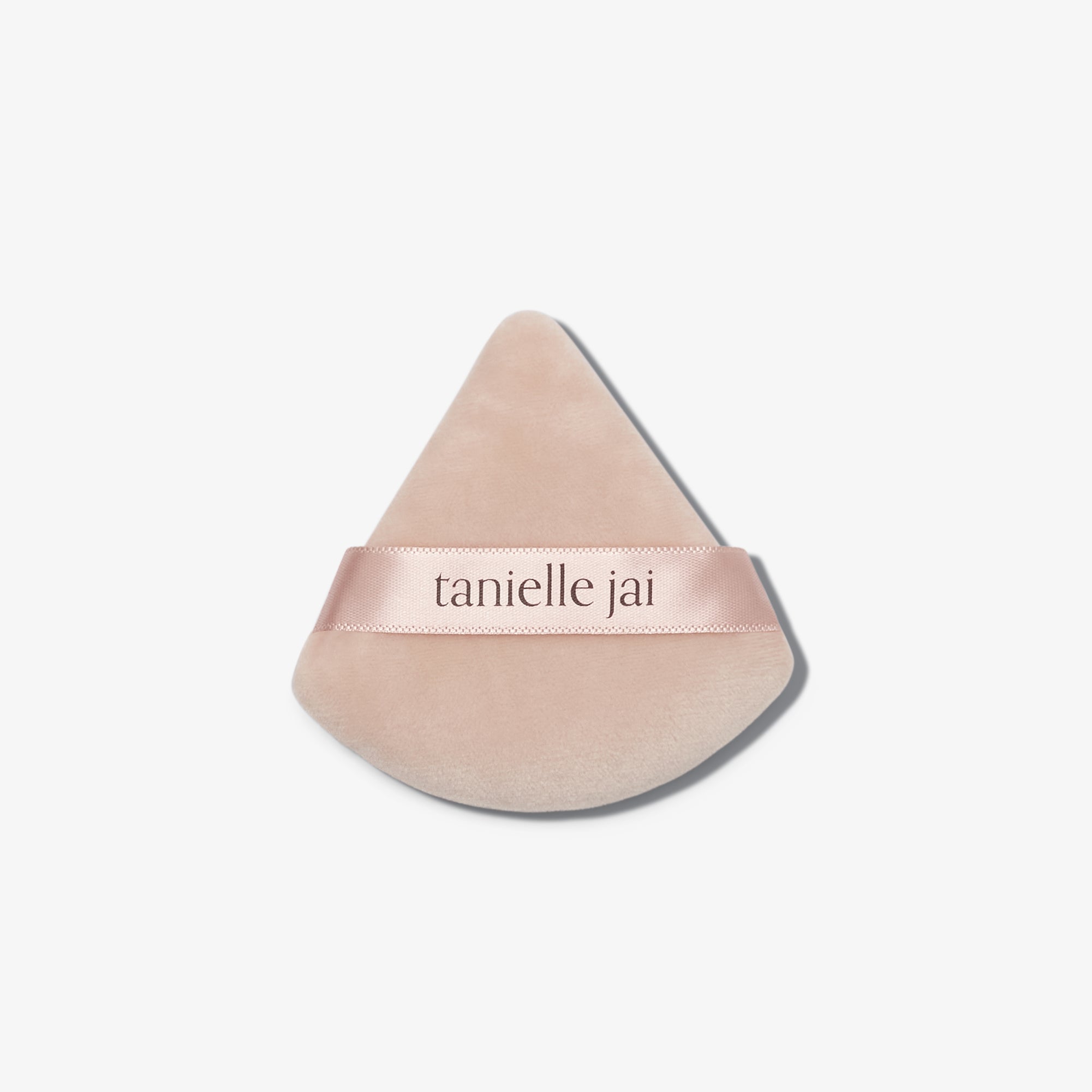 A triangular pink velvet powder puff with the logo 'tanielle jai' written across the center.