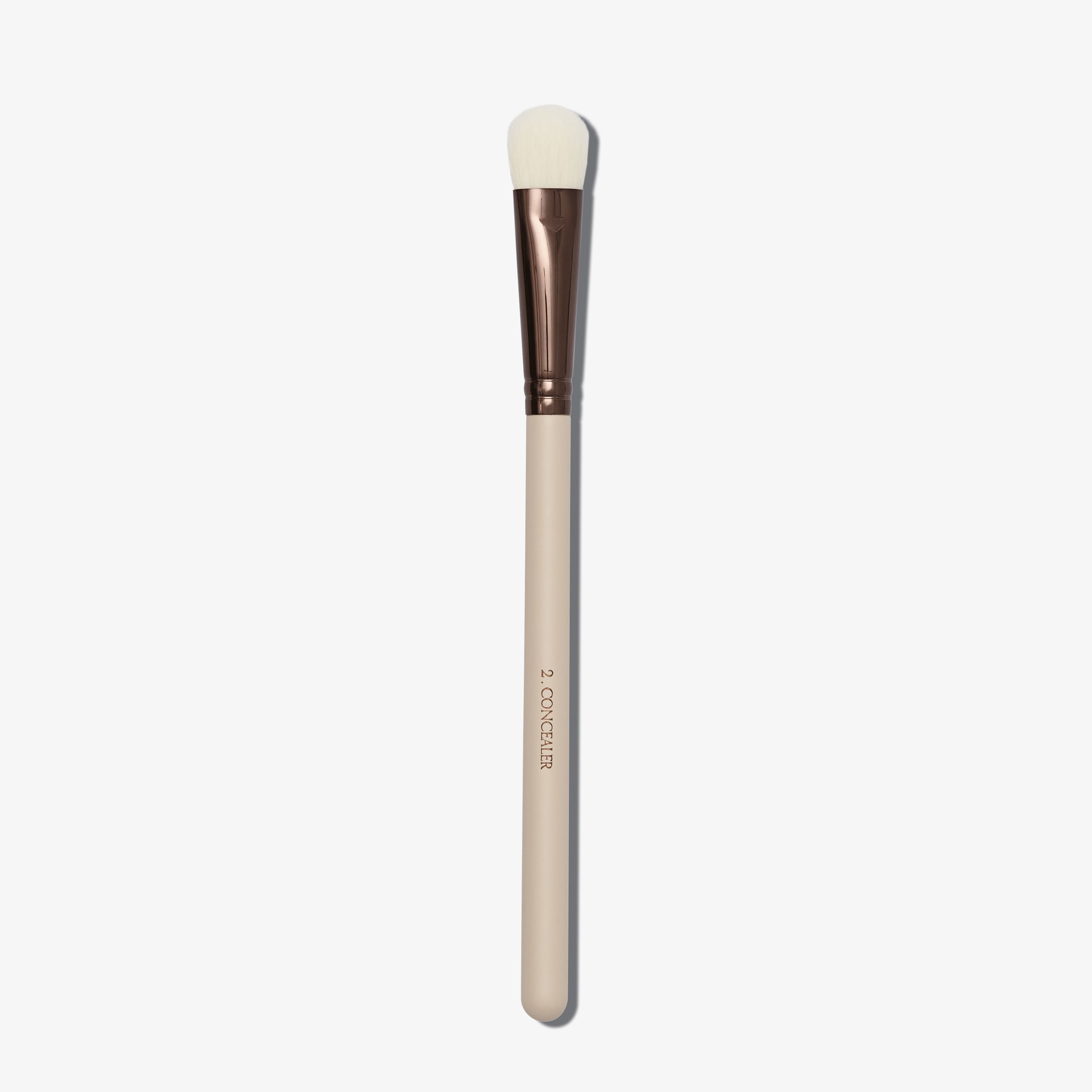 A Concealer brush with a flat, fluffy tip and a beige handle with a copper ferrule.